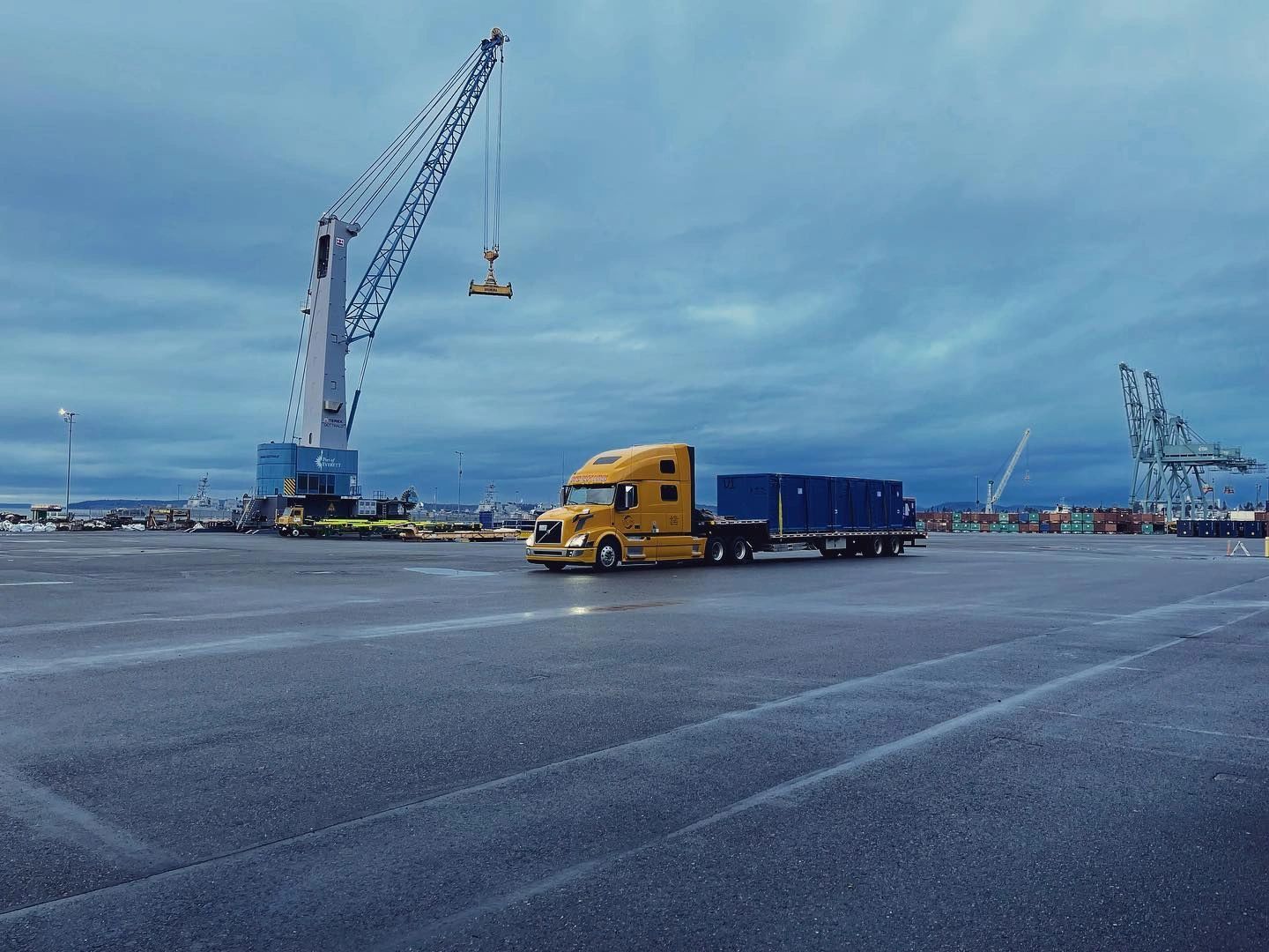 Yellow semi-truck at port facility at twilight